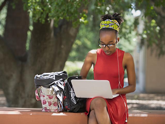 young female uc davis student outside working on a laptop