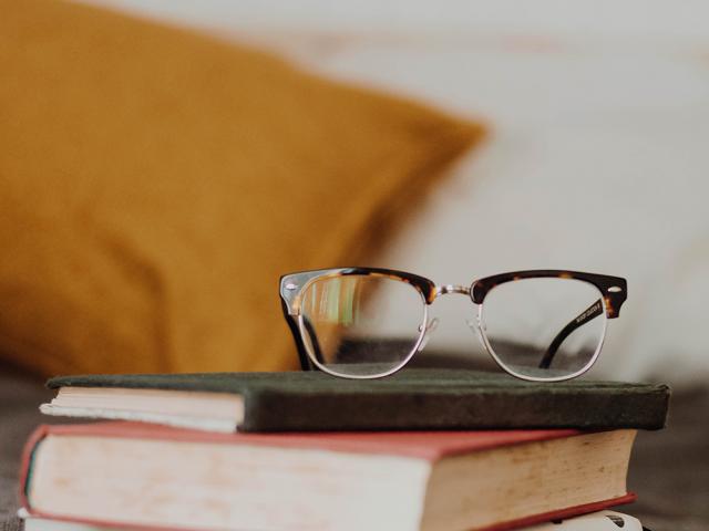 pair of glasses on top of a stack of books